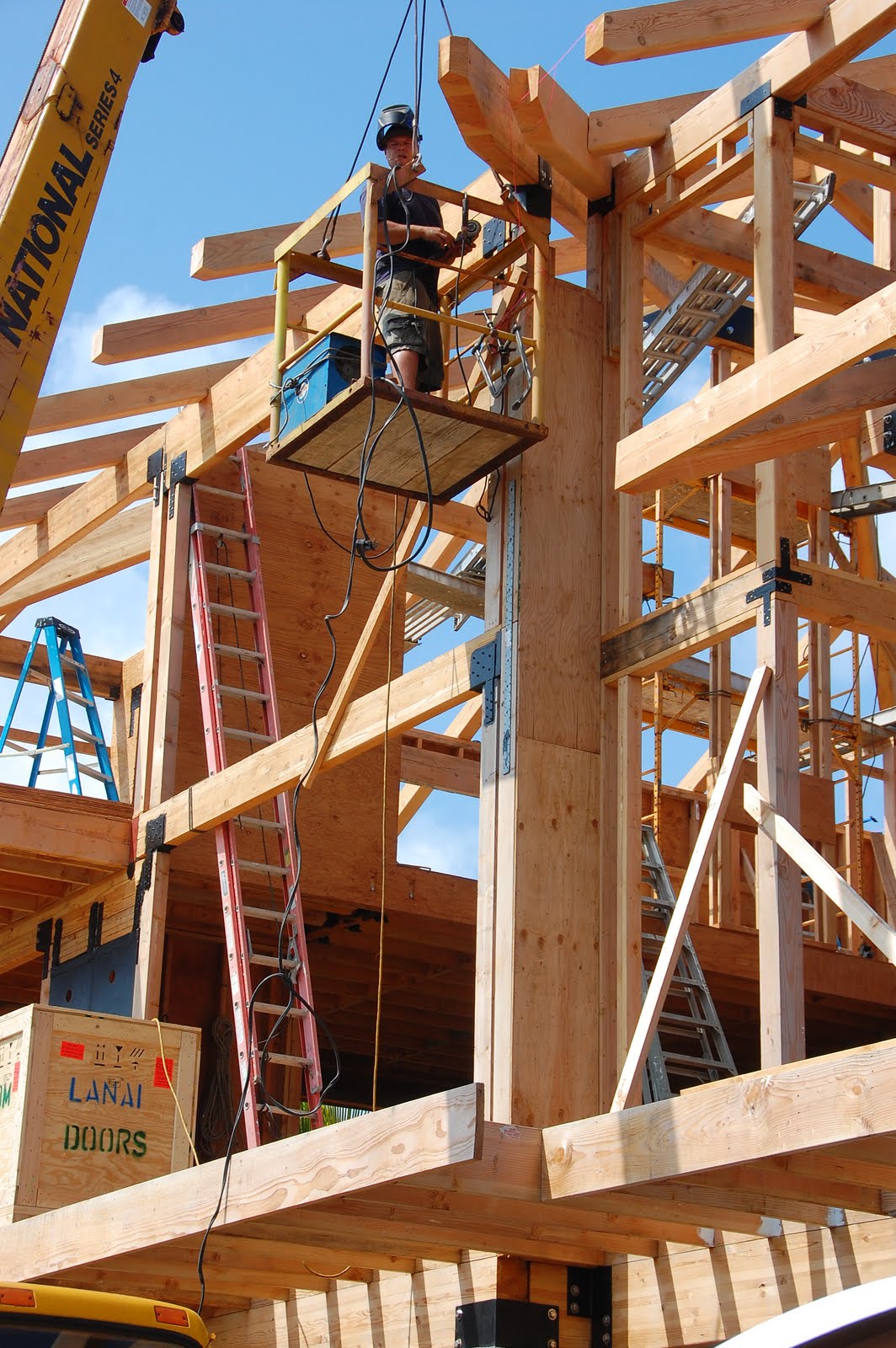 Welder on a lift welding beam supports for the roof on a new home