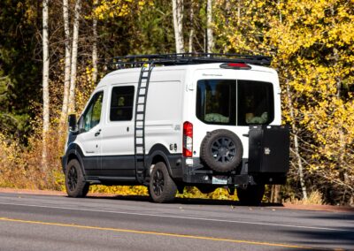 White Sprinter Van on side of road with yellow leaved trees behind