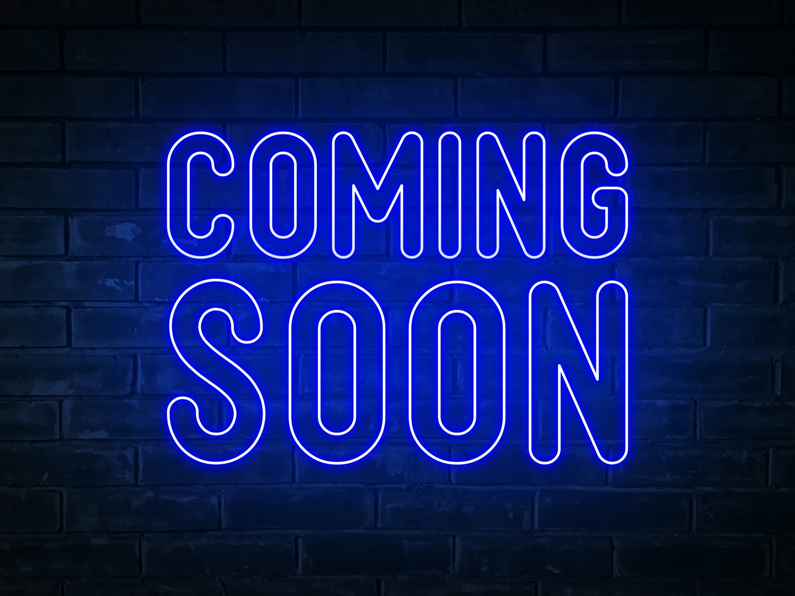 Blue Neon Sign says, "Coming Soon" on black background